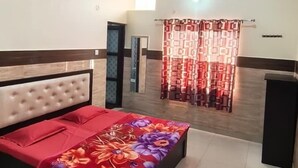 A bedroom with a bed, a ceiling fan, a window with curtains, and a tiled floor. - Sudama Krishna Residency (Mathura)