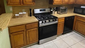 A kitchen with wooden cabinets, a stove, a microwave, and a dishwasher.