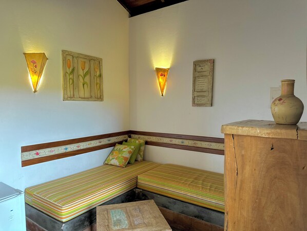 A corner room with a bench, a wooden cabinet, and two wall-mounted light fixtures. - Pousada Fecho da Serra (Capitólio)