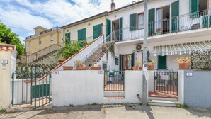 Un edificio residenziale con cancello, una scala che conduce al piano superiore e piante in vaso sul balcone.