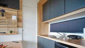 Een moderne keuken met een vaatwasser, een gootsteen en een raam met jaloezieën.