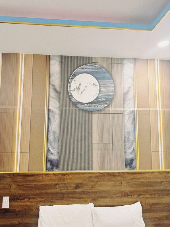 A bedroom with a wooden headboard, a circular wall decoration, and a bed with white bedding.