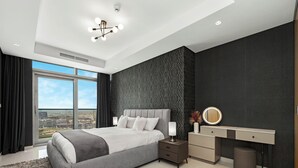 A modern bedroom with a large bed, a bedside table with a lamp, a vanity with a mirror, and a view of the city through a large window. - Spectacular Burj View from Infinity Pool (Dubai)