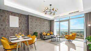 A modern living room with a dining area, large windows offering a city view, and a chandelier. - Spectacular Burj View from Infinity Pool (Dubai)