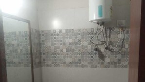 A small bathroom with a toilet, sink, and mirror. - Trovero Suites (Greater Noida)