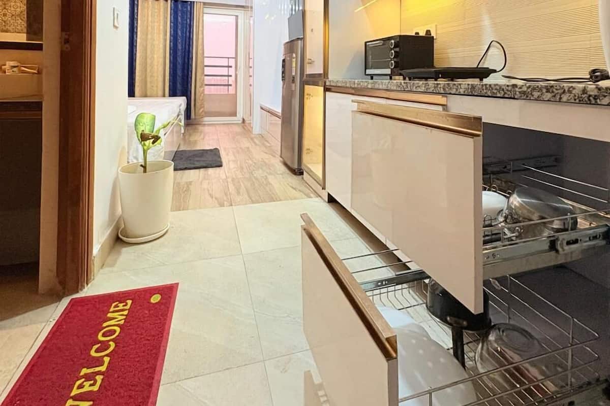 A modern kitchen with white cabinets, a built-in oven, and a microwave. There is a red welcome mat at the entrance.