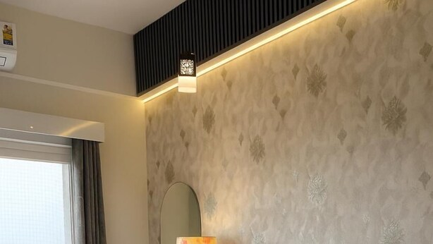 A modern hotel room with a large bed, a bedside lamp, and a view of the outdoors. - Trovero Suites (Greater Noida)