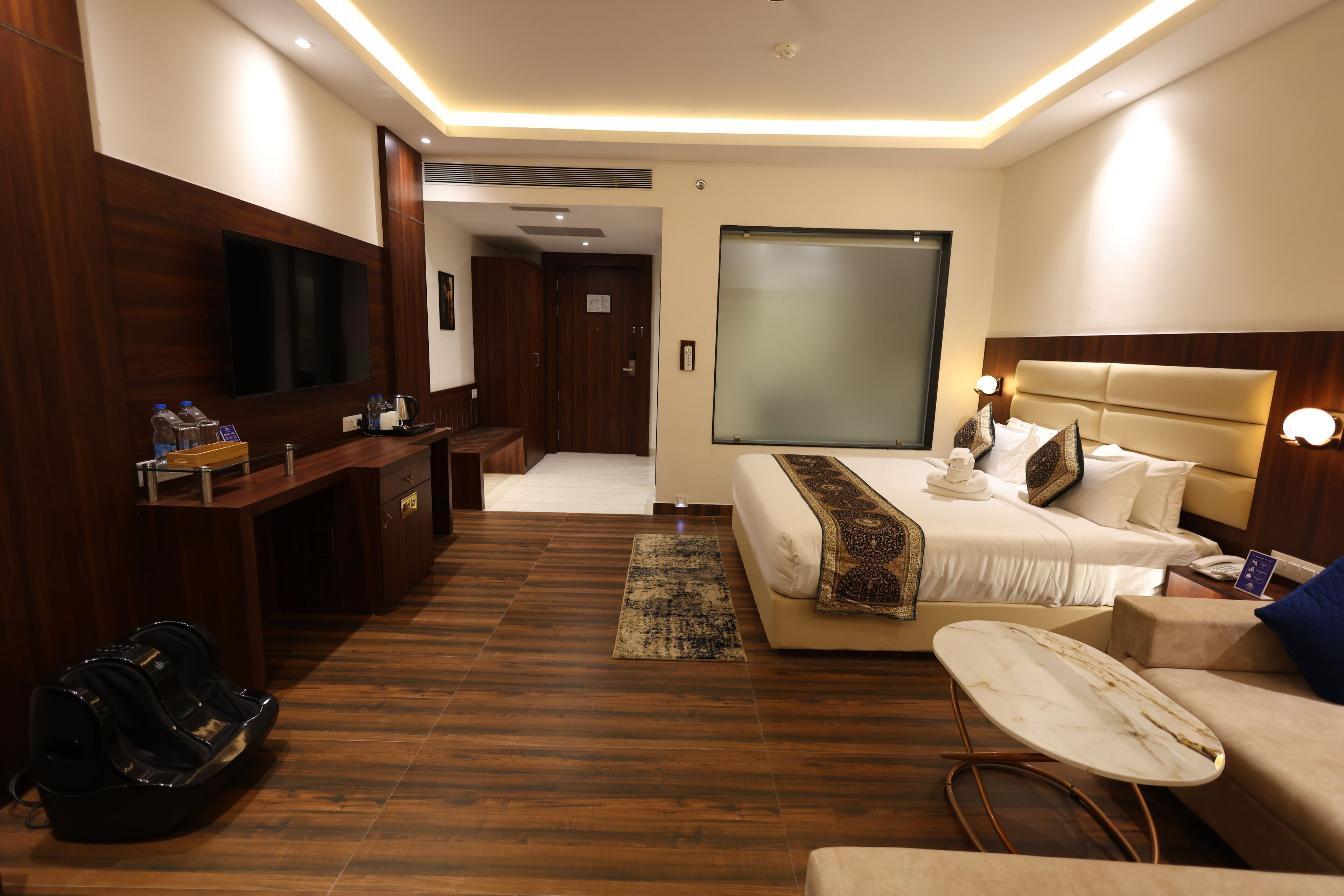 Habitación de hotel con cama, escritorio, televisor y zona de estar.
