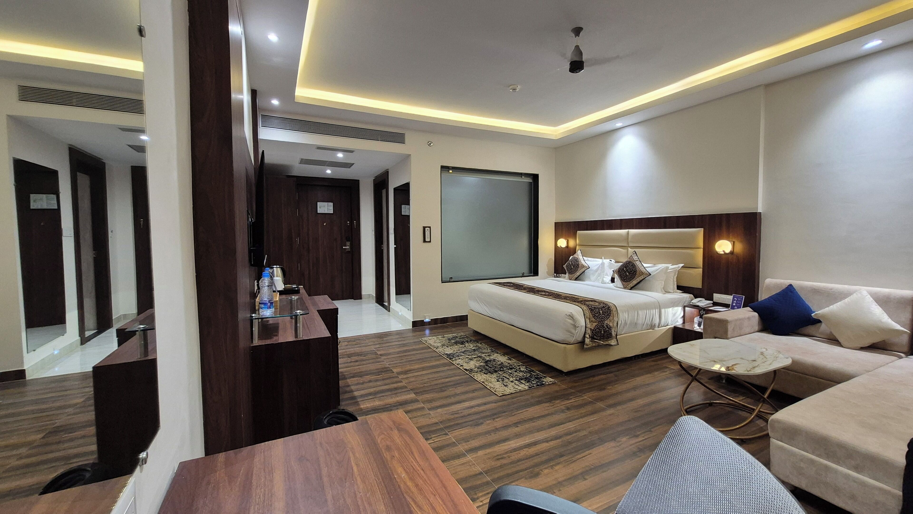 Una habitación de hotel con una cama grande, un sofá, un escritorio y un espejo.