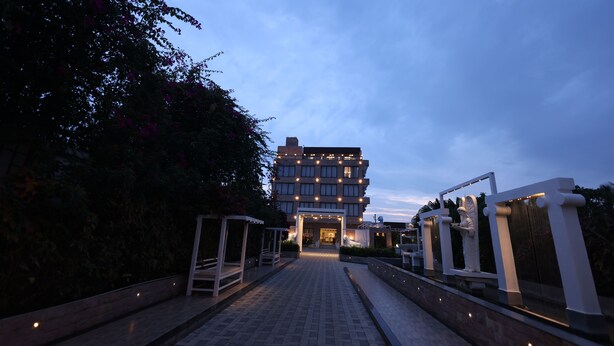 Un bâtiment moderne doté d’une entrée centrale, entouré d’un chemin pavé et de verdure.