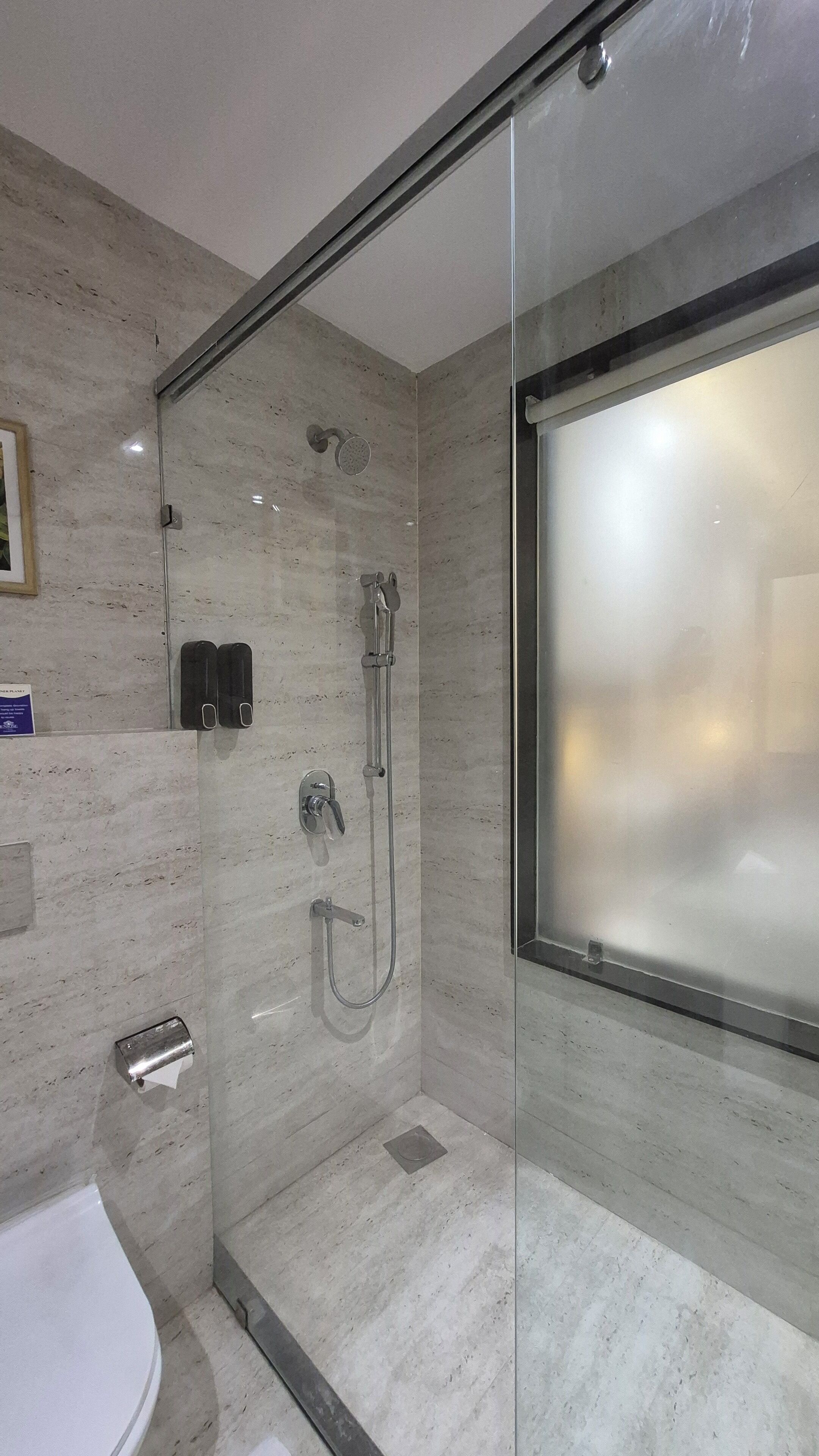 Un baño moderno con ducha de vidrio, inodoro y suelo de mármol.