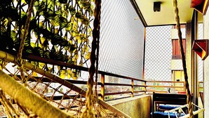 Una hamaca colgada de una estructura metálica, con un edificio a lo lejos.