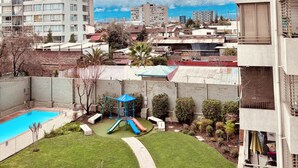 Zona residencial con piscina, área de juegos infantiles y vistas a montañas nevadas.