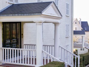 A white building with a covered porch, a brick entrance, and a white railing. - Le Parc de La Jacotte by Interhome (Deauville-Trouville)
