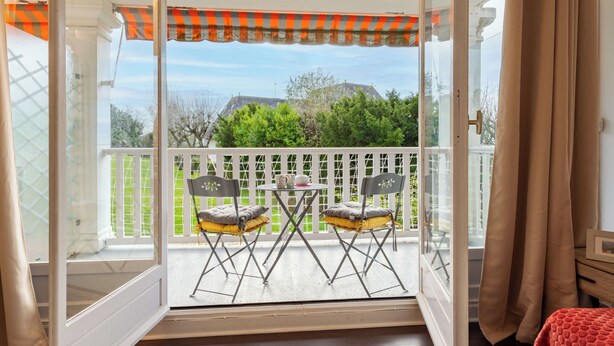 A room with a sliding glass door leading to an outdoor balcony with a white fence, two folding chairs, and a small table. - Le Parc de La Jacotte by Interhome (Deauville-Trouville)