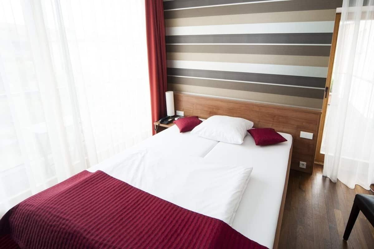 A hotel room with a bed, a nightstand, and a wooden headboard.