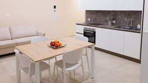 Eine moderne Küche mit weißen Schränken, einer Marmorarbeitsplatte und einem eingebauten Backofen.
