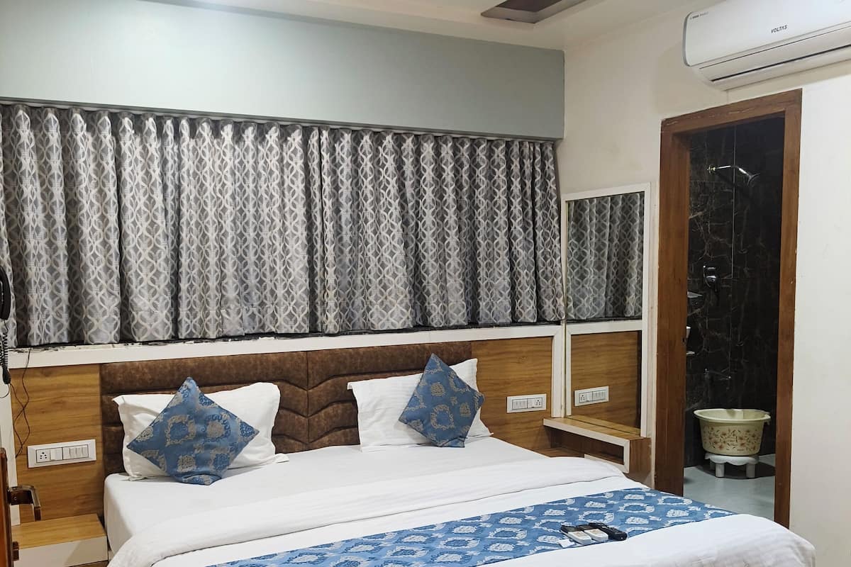 Un dormitorio con cama, ventilador de techo, ventana con cortinas y unidad de aire acondicionado.