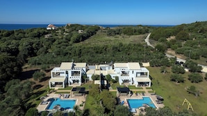 Un moderno resort con due edifici principali, una piscina e vista sul mare.