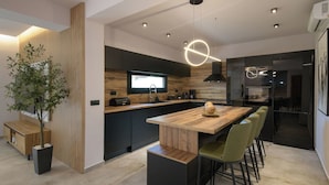 Una cucina moderna con isola in legno, pensili neri e forno integrato.