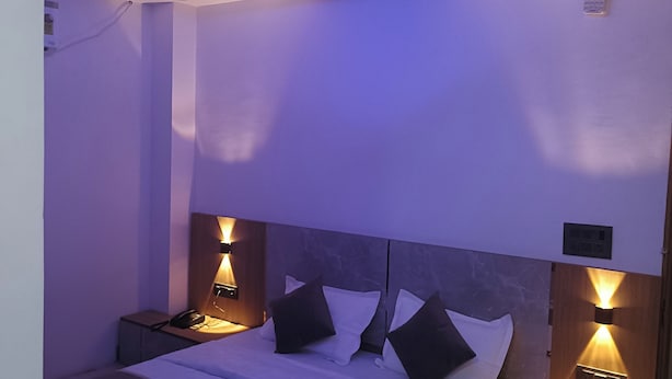 Un dormitorio moderno con cama, lámparas de noche, ventilador de techo y mesita de noche.