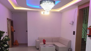 Una sala de estar moderna con un sofá modular, una mesa de centro de cristal y una araña.