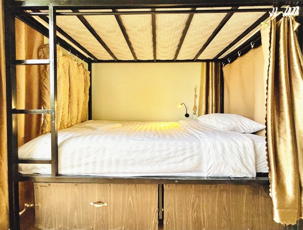 A bunk bed with a headboard, a bedside lamp, and curtains.