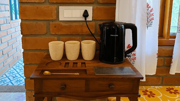 Une table en bois avec une machine à café, trois tasses, une cuillère et un clavier.