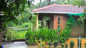 Una casa con techo de tejas rojas, fachada de ladrillo y un pequeño porche con toldo verde.