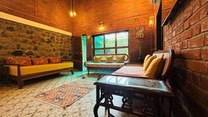 Una habitación acogedora con pared de piedra, un banco de madera, un sofá y una mesa de vidrio.