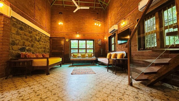 Una habitación acogedora con pared de piedra, banco de madera y una escalera.