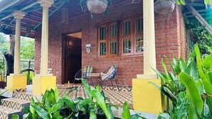 Una casa de ladrillo con porche, una puerta y una ventana.