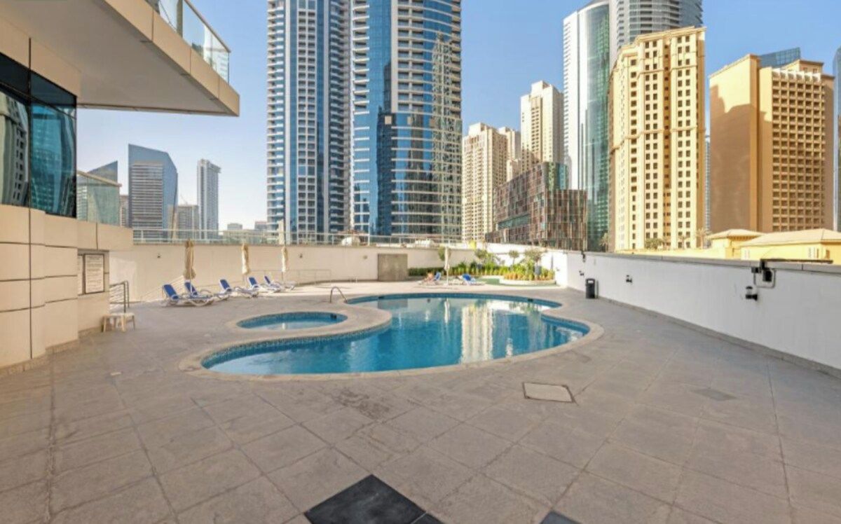 Un espace piscine aménagé sur le toit, avec des chaises longues et une vue sur les immeubles environnants.