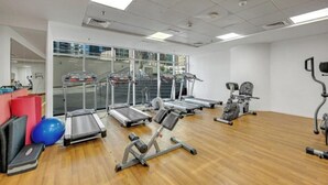 Un gimnasio con cintas de correr, elípticas y pelotas de ejercicio.