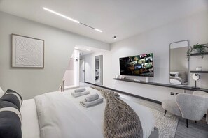 A modern hotel room with a large bed, a flat-screen TV, a mirror, and a sofa. - Skyline / Balcony / Waterfront & Marina Walk (Dubai)