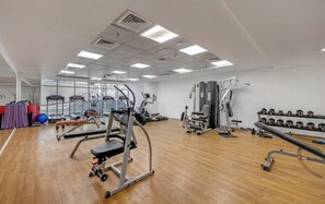 Ein Fitnessstudio mit verschiedenen Trainingsgeräten, darunter Kraftgeräte und Kurzhanteln.