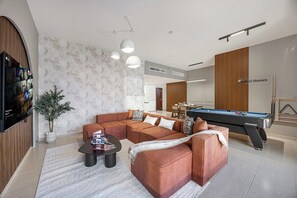 A modern living room with a sectional sofa, a pool table, and a flat-screen TV mounted on the wall. - Palm Views / Pool Table / Gym / Pool / opp Beach (Dubai)