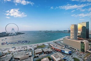 A coastal cityscape with a prominent Ferris wheel, beachfront, and modern high-rise buildings. - Palm Views / Pool Table / Gym / Pool / opp Beach (Dubai)