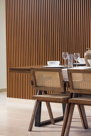 A dining area with a table set for two, featuring a woven chair design and a wooden backdrop. - Palm Views / Pool Table / Gym / Pool / opp Beach (Dubai)