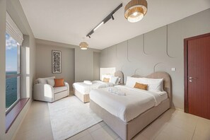 A modern bedroom with a large bed, two smaller beds, a sofa, and a view of the sea. - Palm Views / Pool Table / Gym / Pool / opp Beach (Dubai)