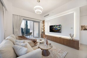Een moderne woonkamer met een zithoek, een salontafel en een aan de muur bevestigde televisie.