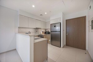 Eine moderne Küche mit weißen Schränken, einem Edelstahlkühlschrank und einer Holztür.