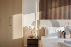 Ein Hotelzimmer mit einem Bett, einem Nachttisch, einer Lampe und einer Vase mit Trockenblumen.