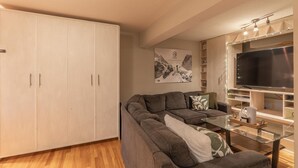 A living room with a sofa, a glass coffee table, a TV, and a wardrobe.