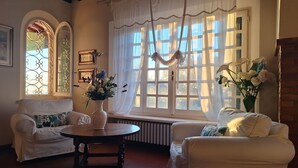 Uma sala de estar acolhedora com dois poltronas brancas, uma mesa de madeira e um vaso de flores.