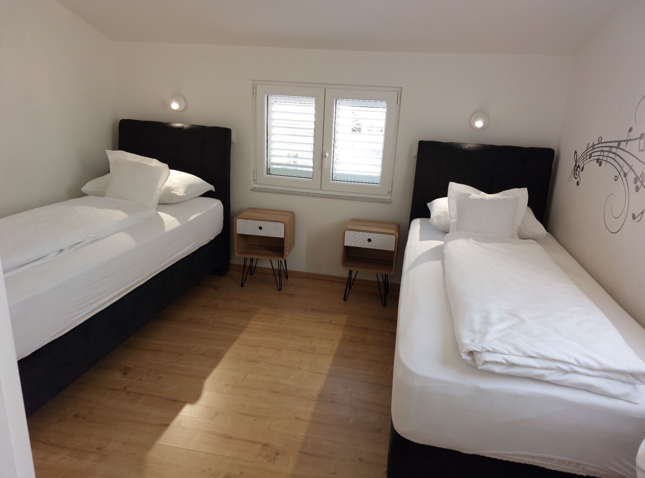 Una habitación con dos camas, una ventana y una mesita de madera.