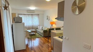 A compact living space with a kitchenette, a dining area, and a seating area with a sofa and a table. - Villa Nižić Makarska (Makarska)