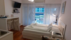 A hotel room with a bed, a desk with a chair, a TV, and a balcony view. - Villa Nižić Makarska (Makarska)