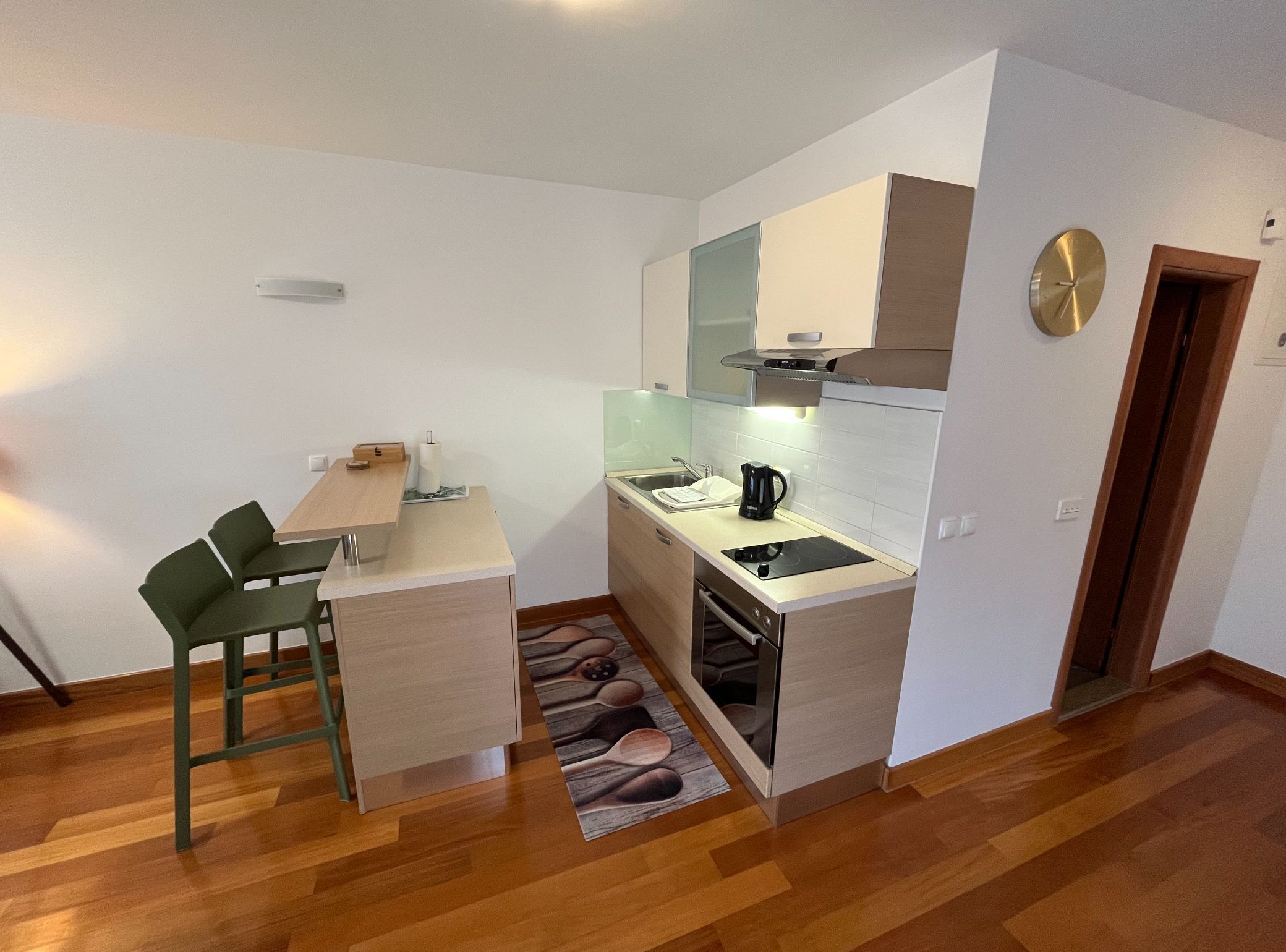 A compact kitchen with a sink, stove, and a small dining area with a chair.