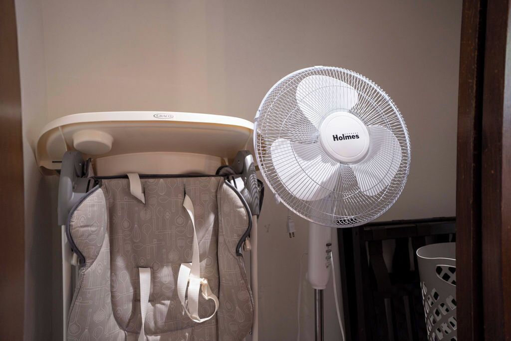 Un baño con inodoro, toallero y ventilador de pie.